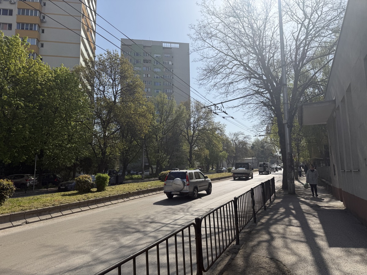 A Pleven street with trolley bus wires overhead, a silver SUV on the road, shadows stretching across the pavement